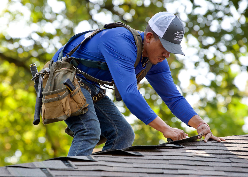 Spruce Up NW cew member on roof fixing shingles to prevent common causes of roof leaks on a Portland home.
