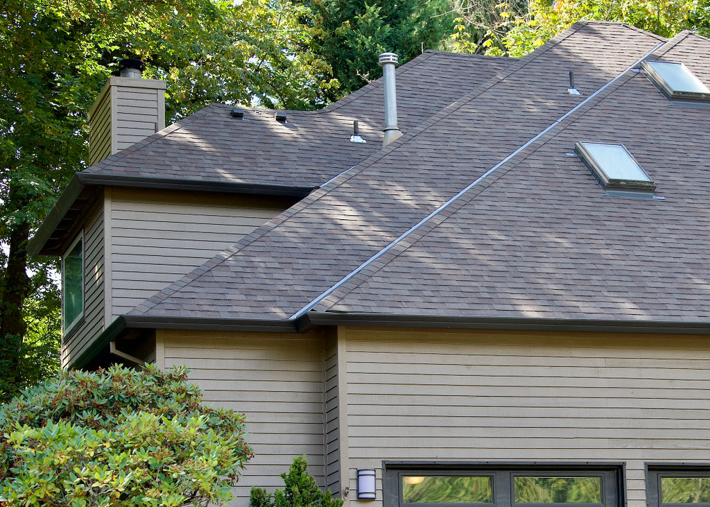 Two story home in Portland, OR after roof maintenance project surrounded by trees and bushes