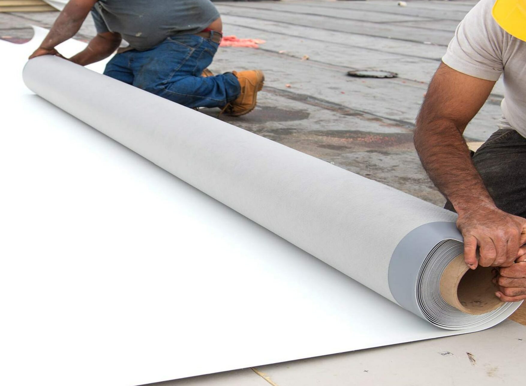 Roofer laying down PVC roofing material