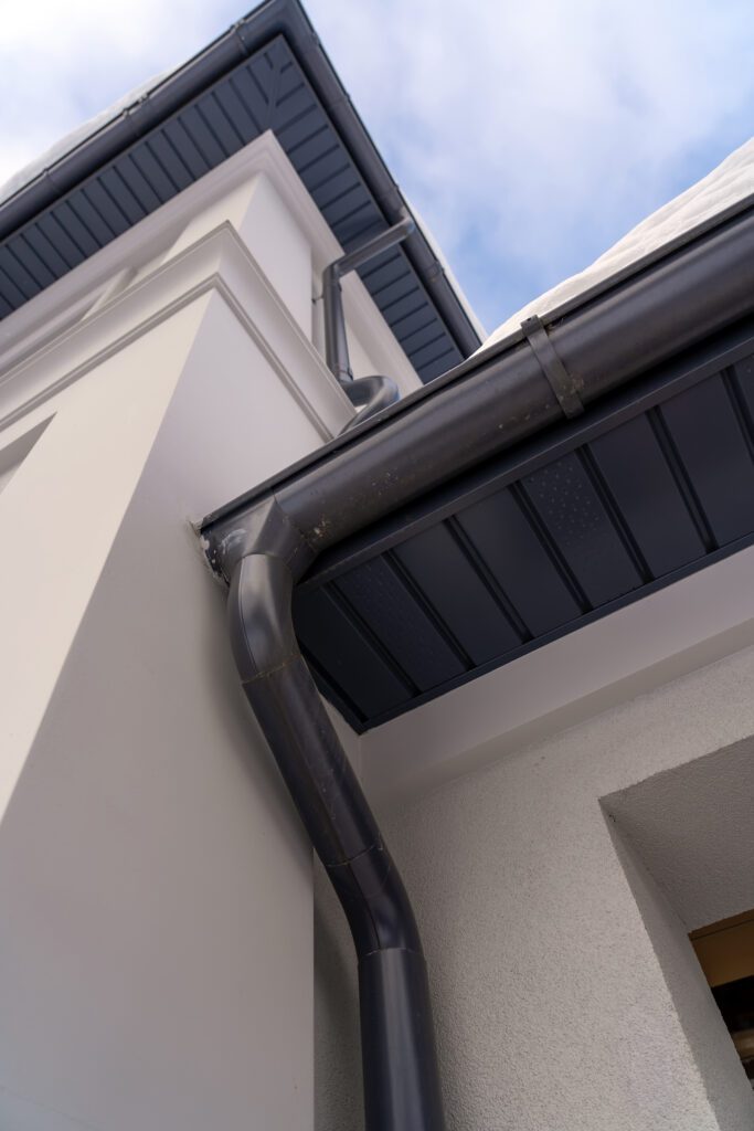 A new black metal gutter on an upscale home to represent full gutter replacement services.