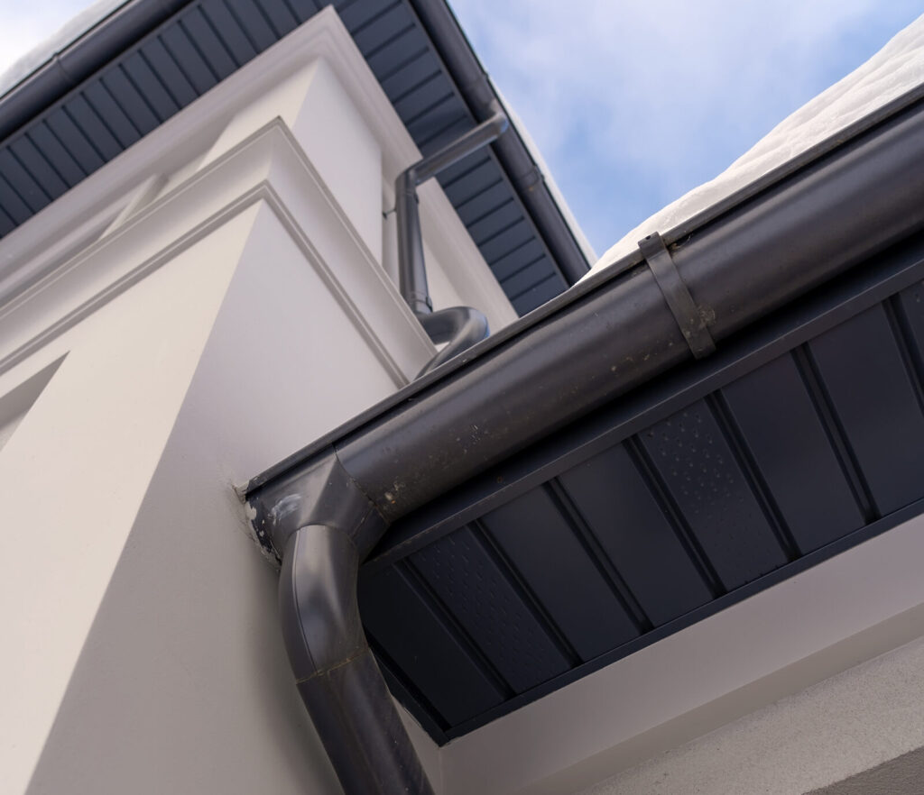 A new black metal gutter on an upscale home to represent full gutter replacement services.