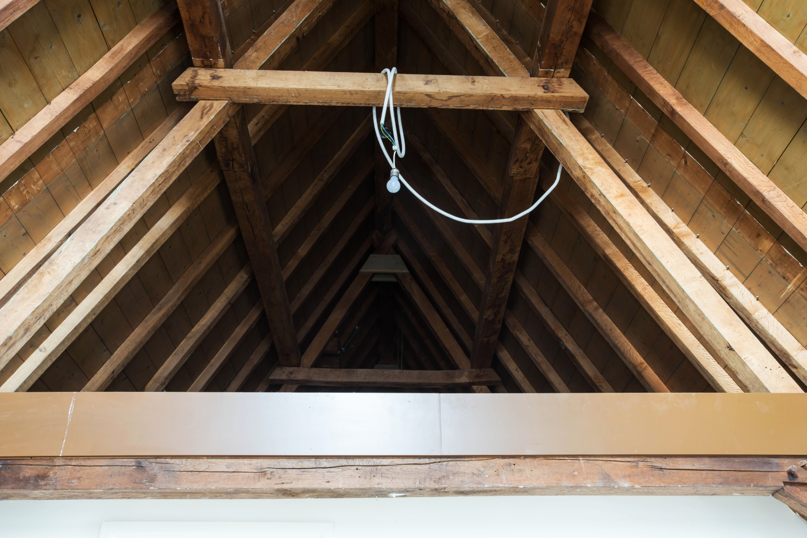 An empty attic with exposed beam to help illustrate attic ventilation services and Things to Look for in a Good Roof Inspection