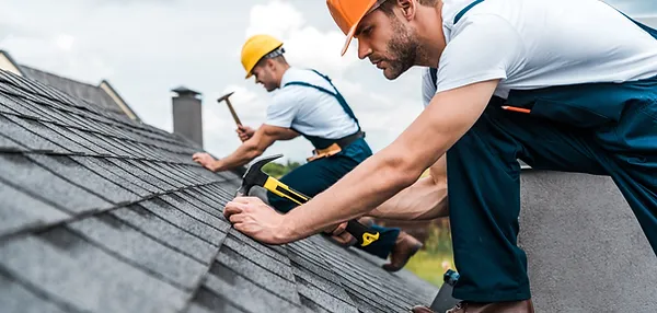 two roofer hammering roof nails in to secure shingles